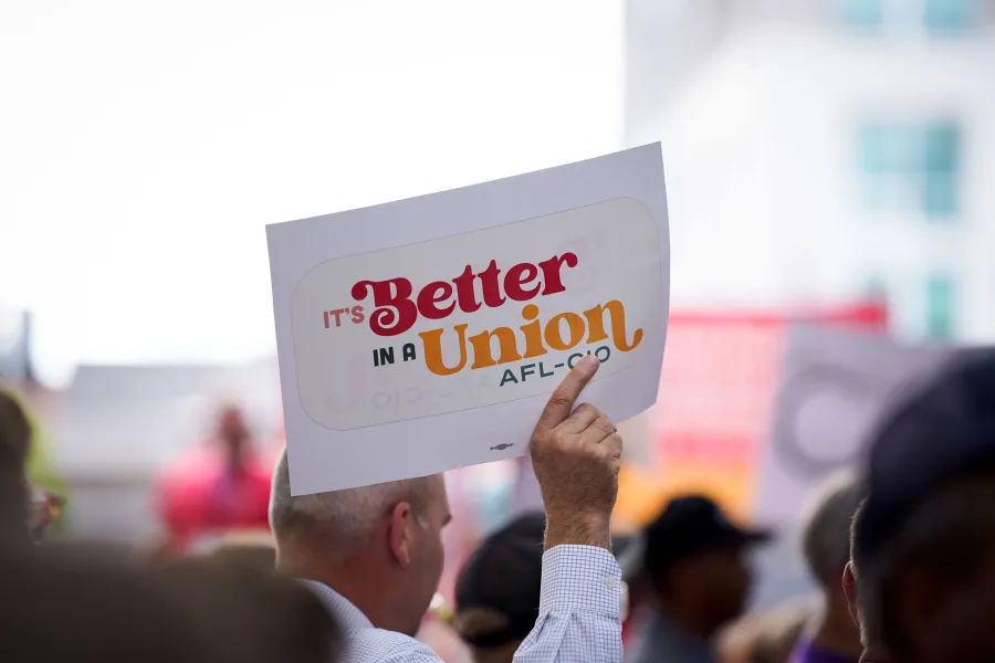 hand holding up a sign that reads "it's better in a union, afl-cio"