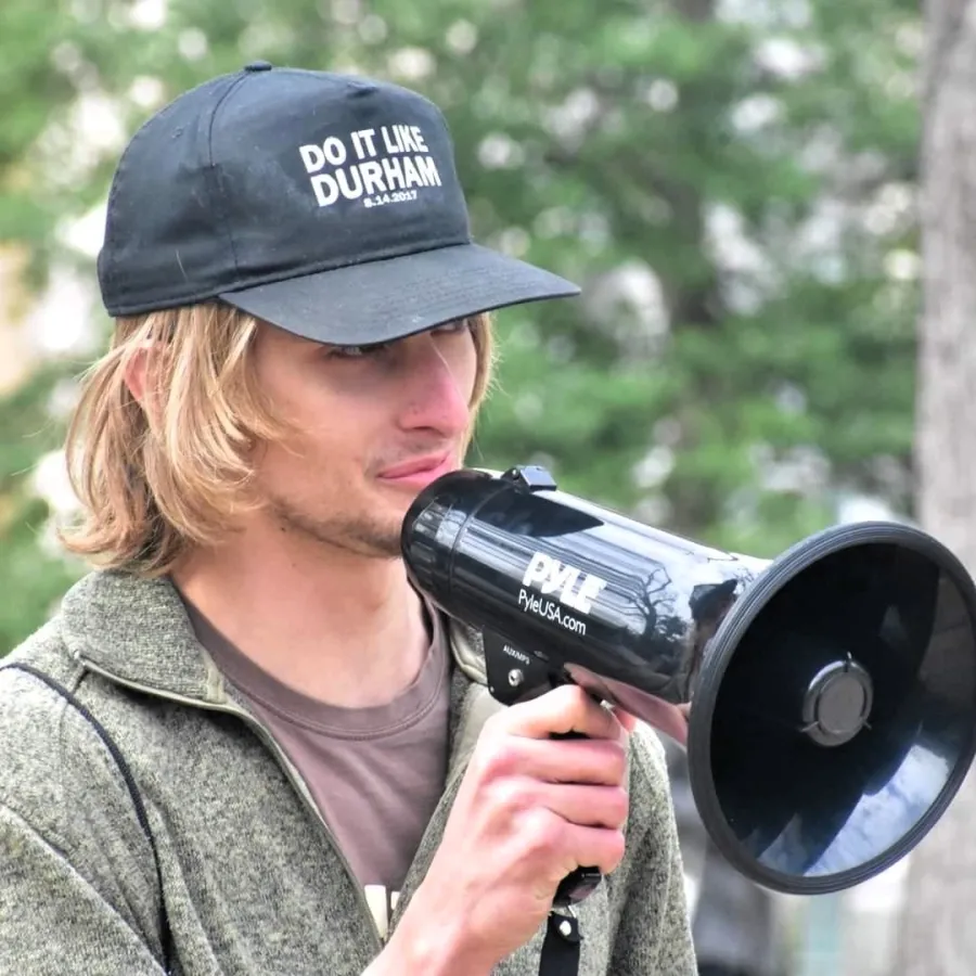 photo of jody anderson wearing a hat that reads do it like durham and holdnig a bullhorn up to his mouth