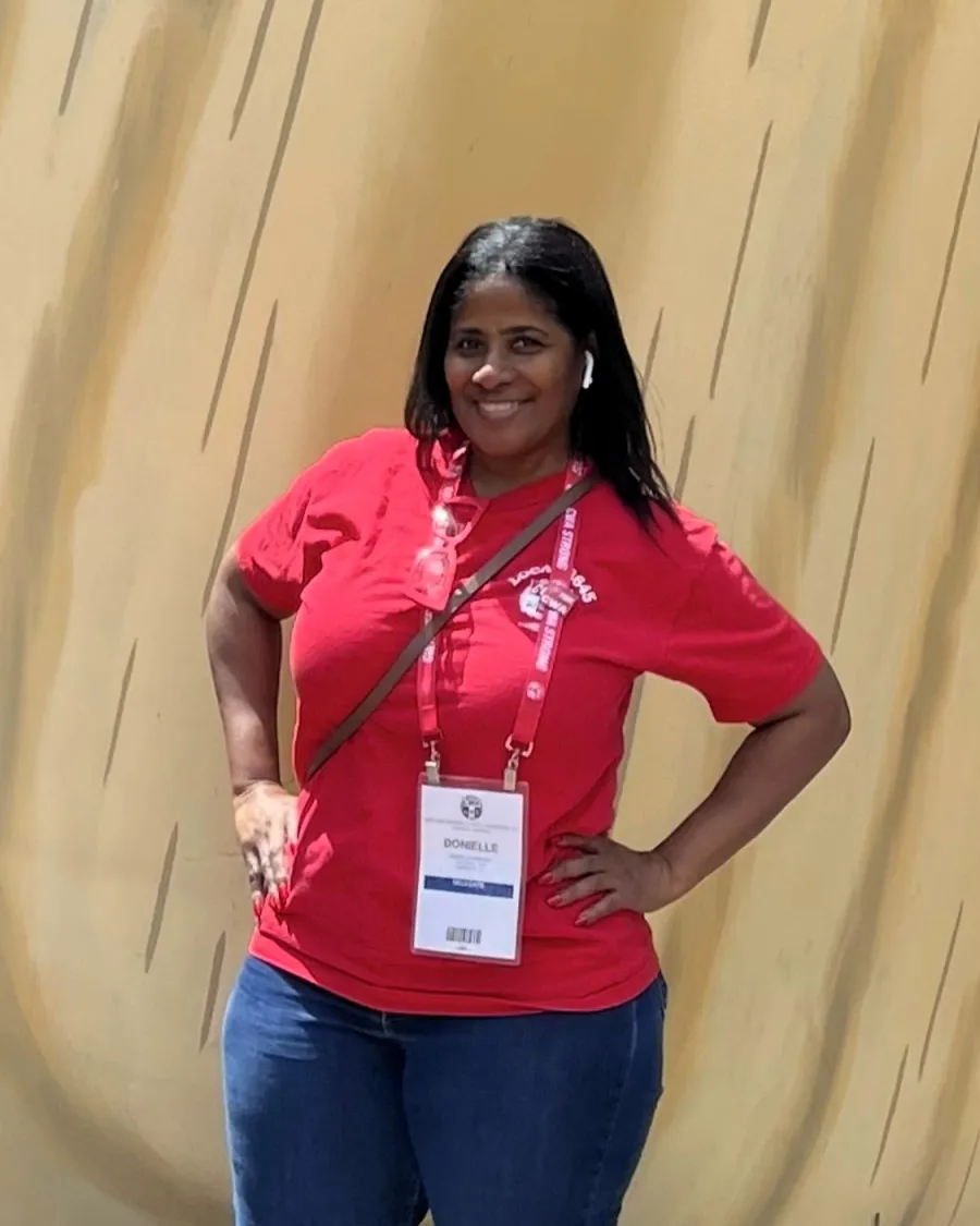 photo of Donielle Prophete wearing a red union t-shirt and blue jeans with her hands on her hips and smiling
